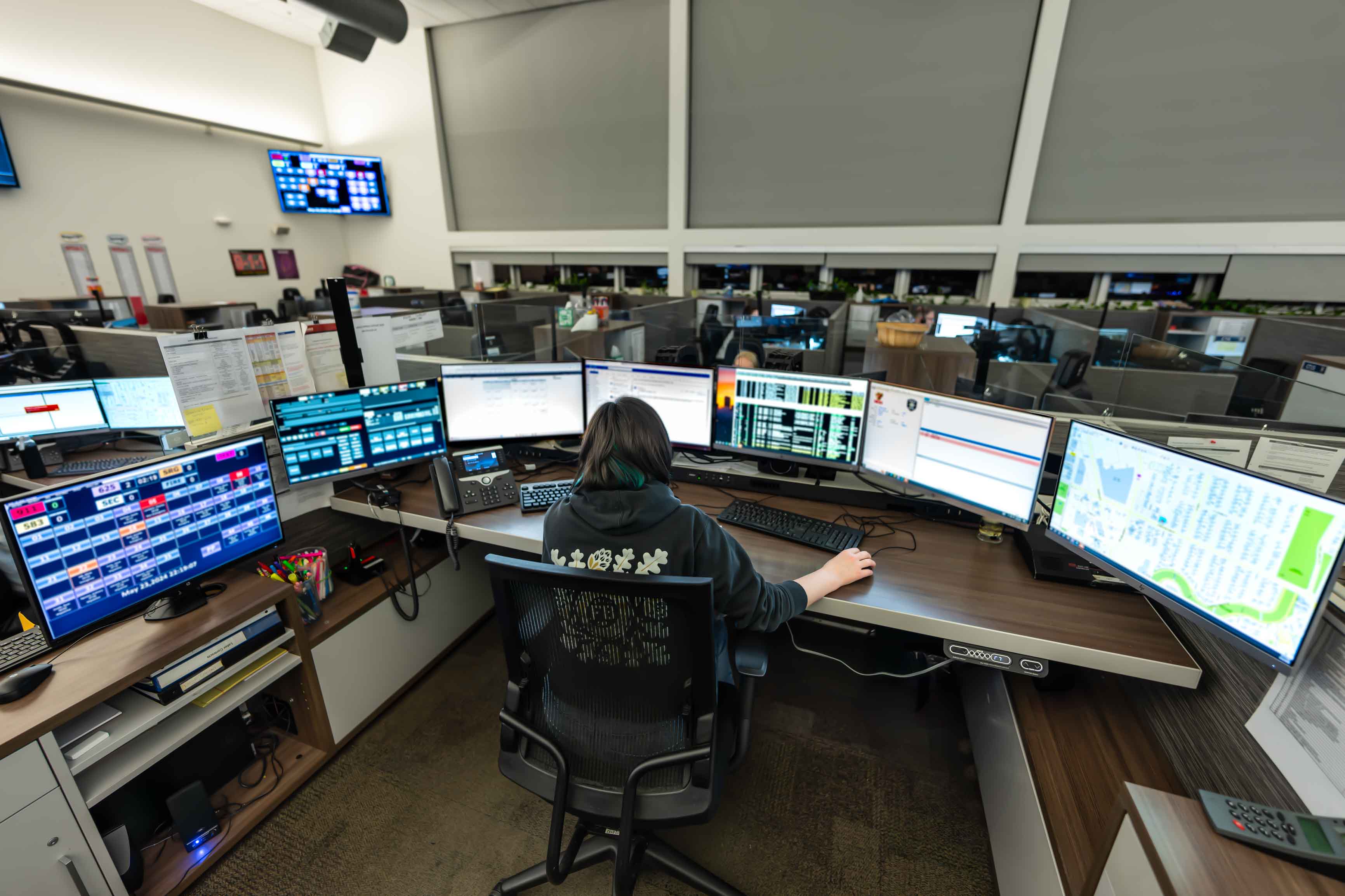 Seattle 9-1-1 dispatcher seated in front of her desk with multiple computer monitors.