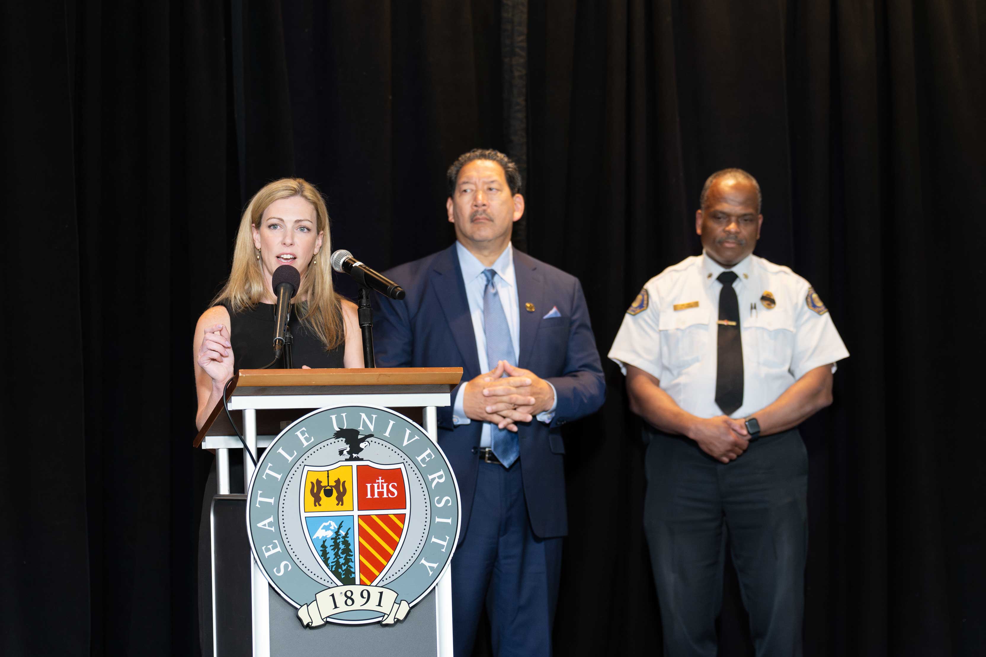Chief Barden, speaking at podium next to Mayor Harrell and Chief Scoggins