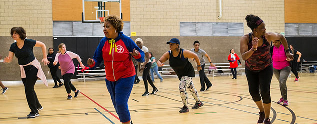 Group of middle aged people exercising at a dance class in a gym.