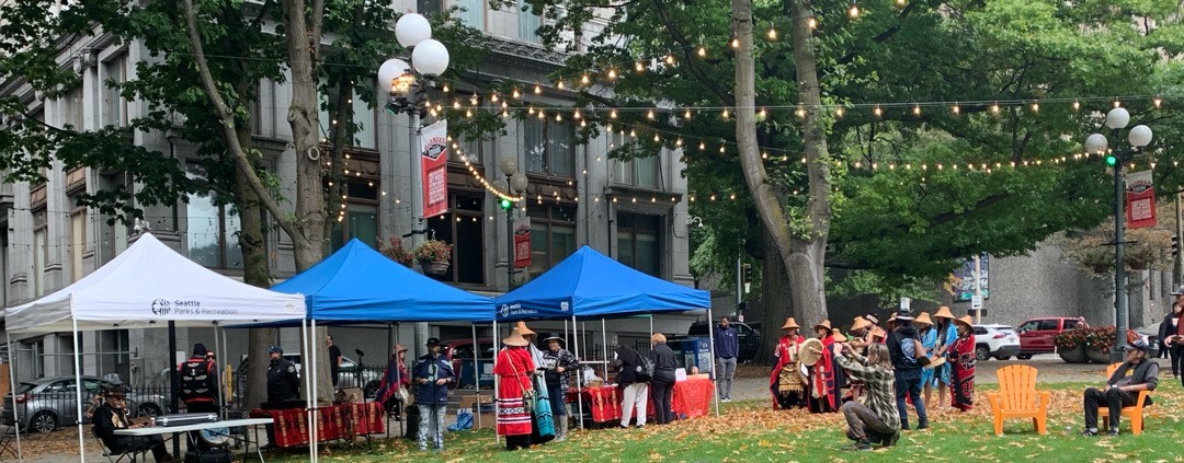Powwow at City Hall Park with many people in attendance wearing traditional hats and cloaks