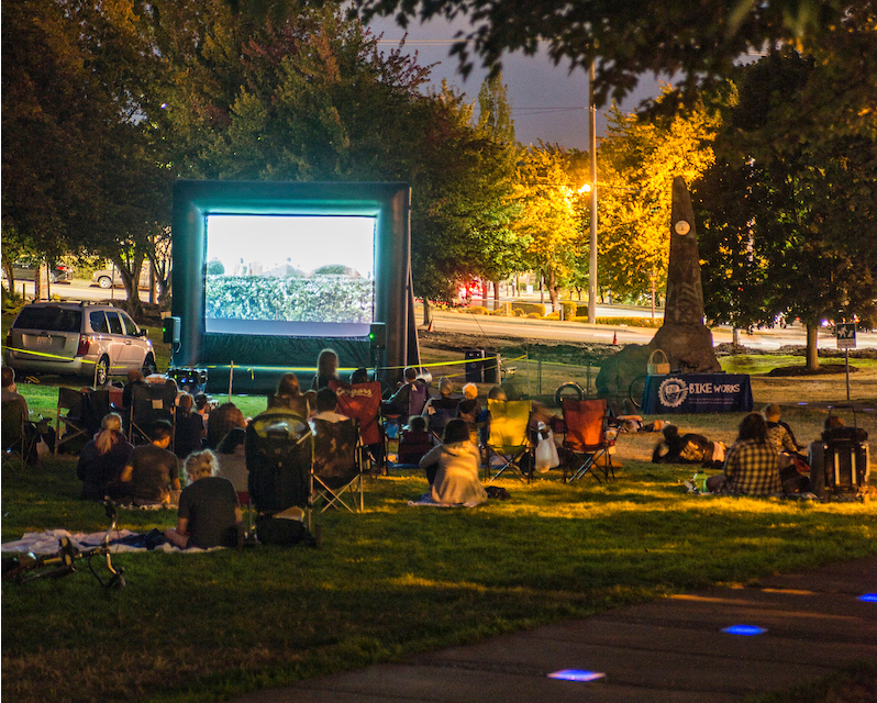 People watching a show on an outdoor projection screen in a park
