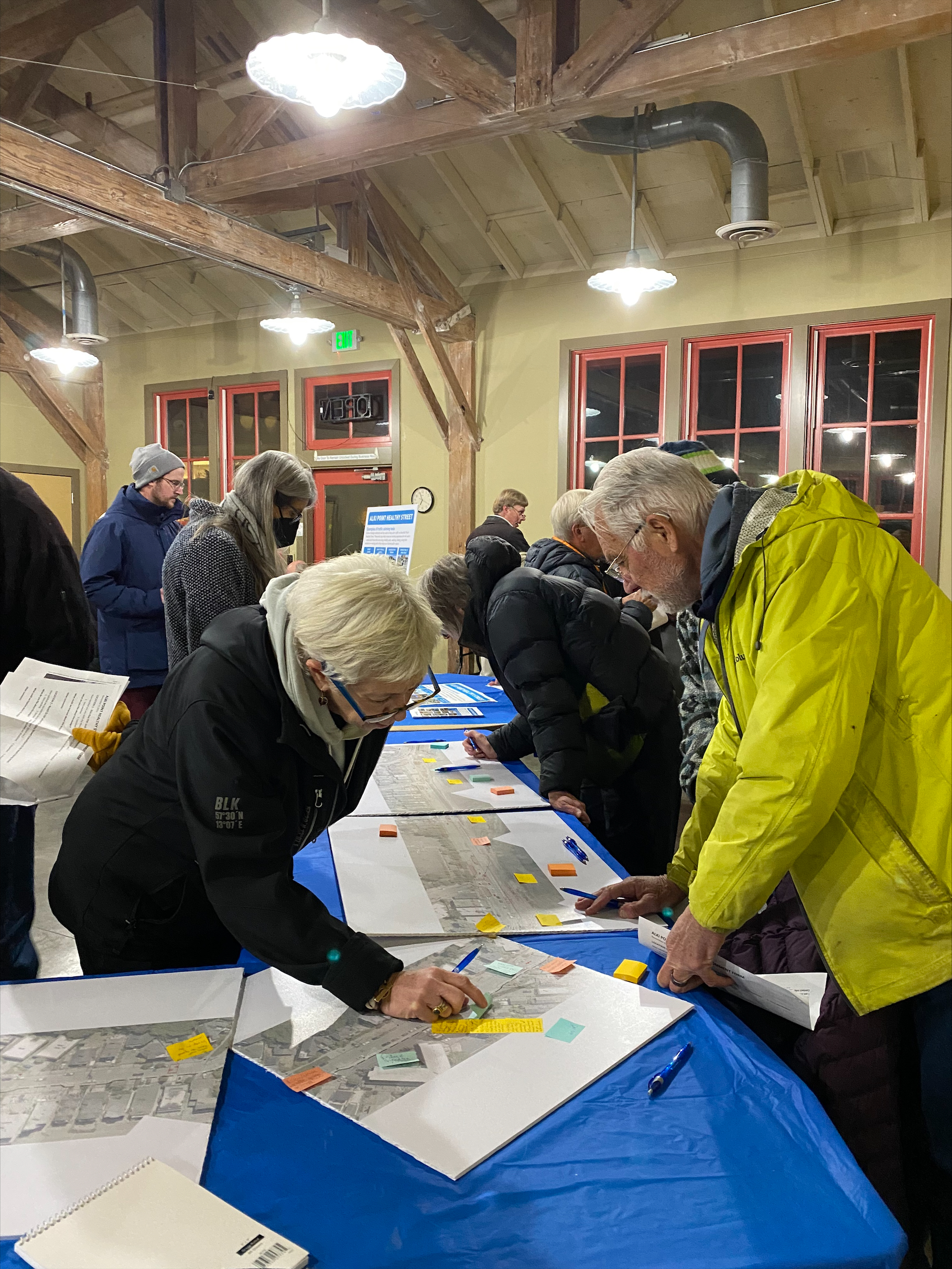 People gather at an open house and view proposed designs and materials on tables