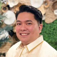 Lanvin has dark black hair, is wearing a creme colored shirt and is smiling