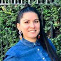 Meriela has long black hair, earrings and is wearing a denim shirt