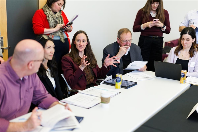 Mayor Wilson sitting at a table with four other people gesturing with her hands as she talks