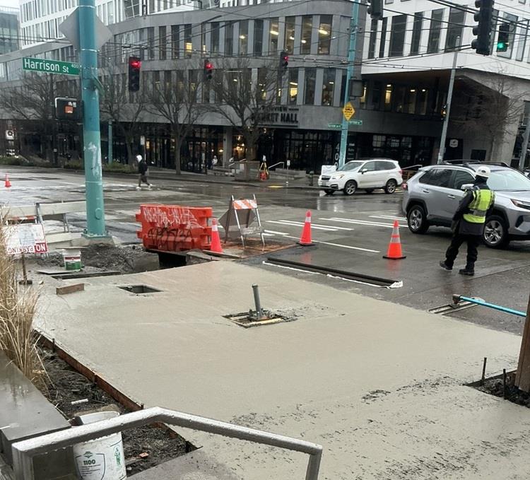 Image shows the team building new concrete pedestrian ramps and installing electrical wires at Fairview Ave N and Harrison St