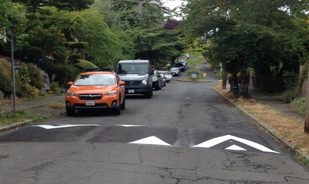 A street with vehicles traveling over speed humps