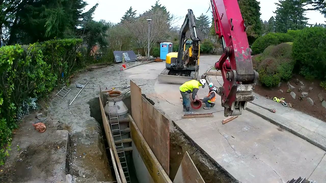 Workers in high-visibility vests and hardhats work in a deep trench on a Seattle street. 
