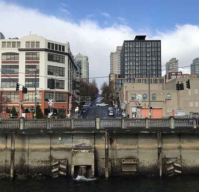 Combined sewer overflow structure with Elliott Bay in the foreground and buildings in the background.