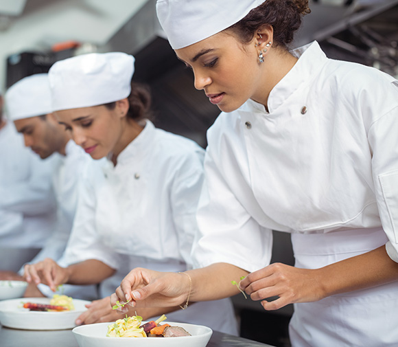 Chefs preparing food in a restaurant kitchen.