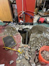 በሲሚንቶው ሥር የተጋለጠ የቧንቧ መስመር ያሚያሳይ የተቆፋፈረ የወለል ክፍል 