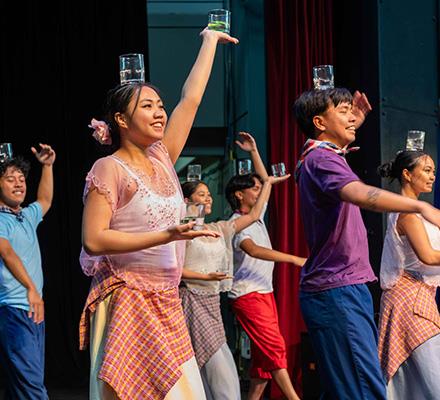 Filipino dancers balance glasses of water on a stage
