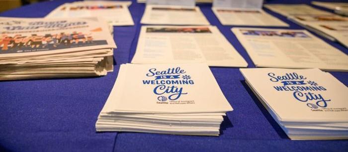 Close up of a stack of resources on a table with one flyer reading Seattle is a Welcoming City.