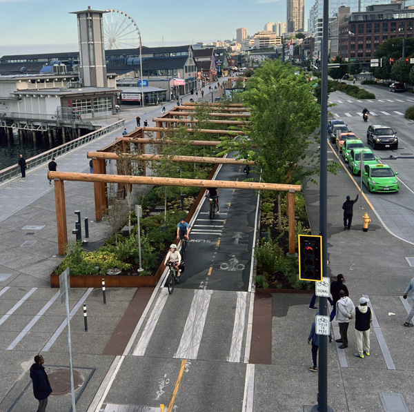 Bicylists biking underneath large wooden structures