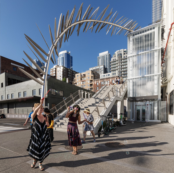 People blowing bubbles in front of Unfurling a Gesture sculpture