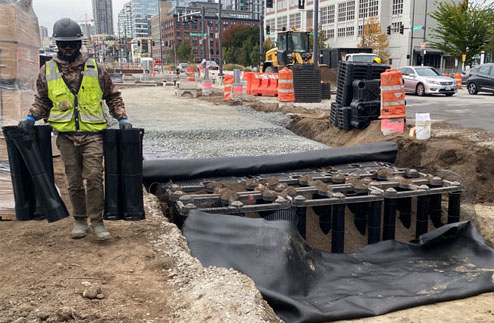 A worker installing soil cells below the protected bike lane and sidewalks
