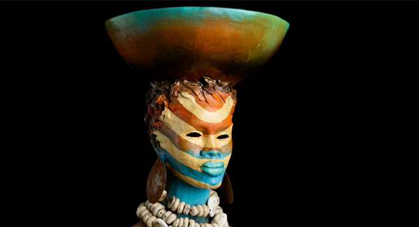 A colorful bust statue of a woman with a bowl on her head
