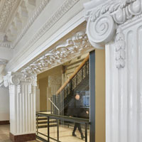 Ornately molded plaster pillars frame a large modern window.