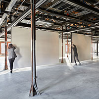 Three people lean against floating walls to move them.