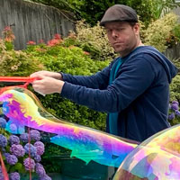 Michael holds a bubble wand and makes a long bubble.