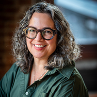 Tina has long, wavy hair and cool glasses.