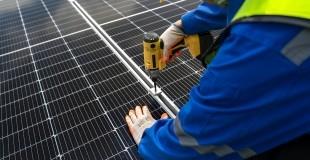 Worker using a drill to install a solar panel.