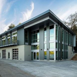 The front of a brand new building with tall glass windows on a concrete plaza