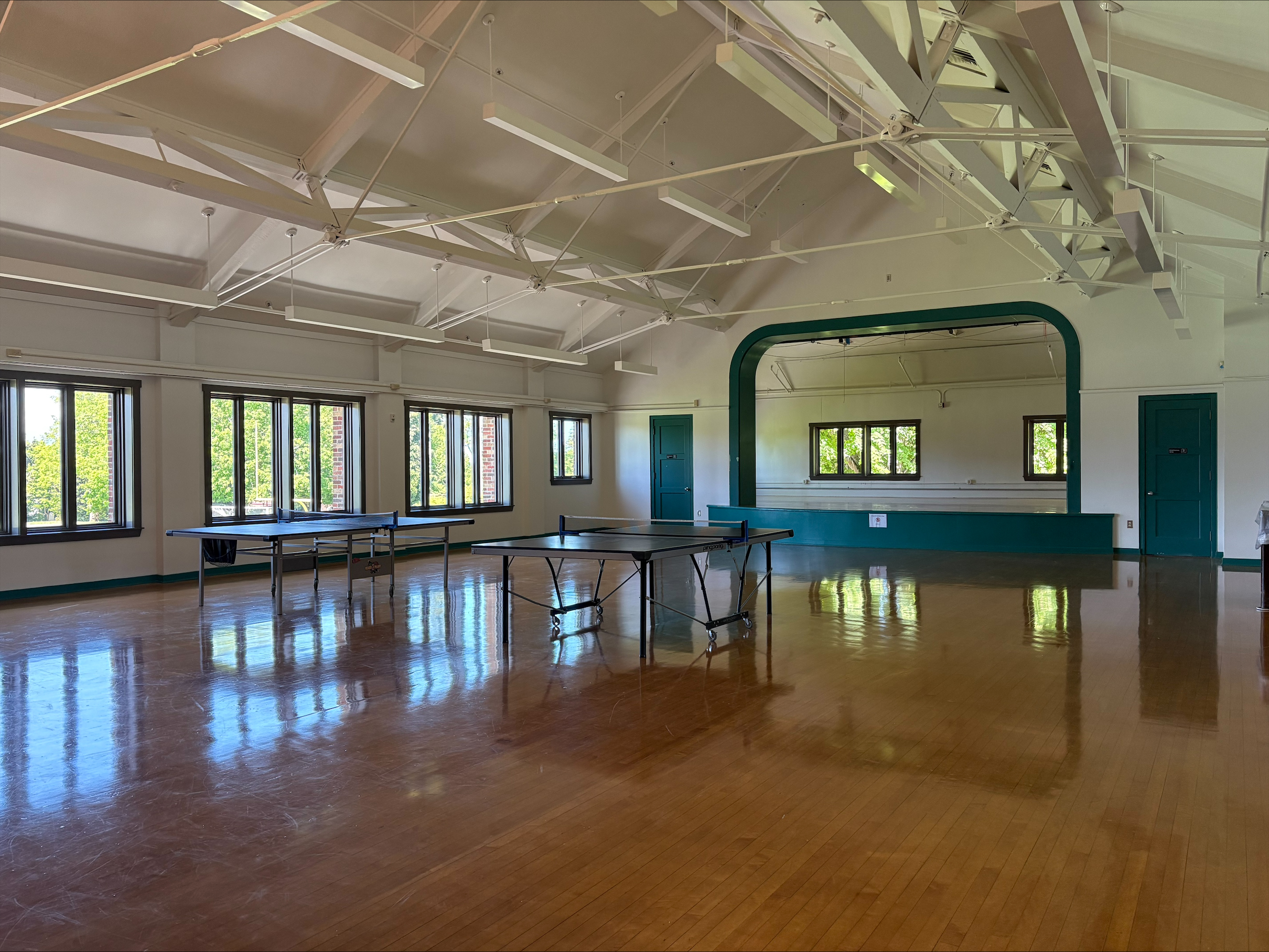 The interior of a large gym-like room with high ceilings and shiny wooden floors
