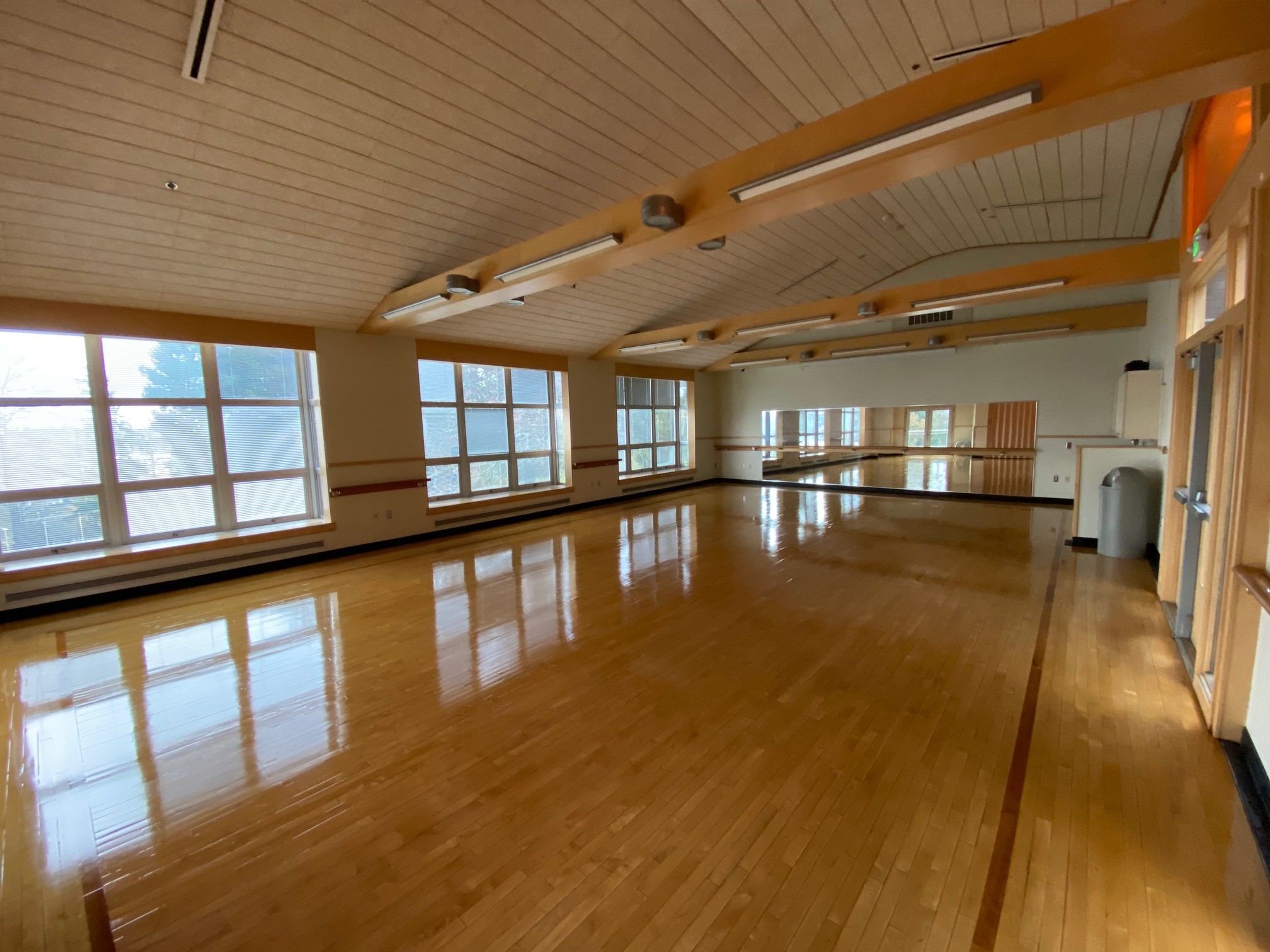 A large open room used as a gym or a conference room, with polished floors and many windows.