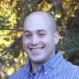 A smiling man in front of trees