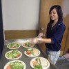 A teen prepares to serve salad on plates