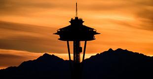 Space Needle at Dusk with golden sky in background above mountain range.