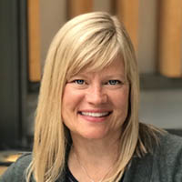 Photo of Christa Dumpys, smiling against an indoor background