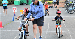 A school age children riding their bikes in chalk drawn lanes