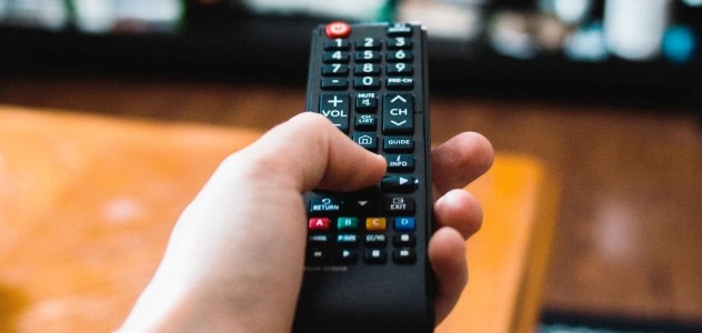 A hand holds a television remote