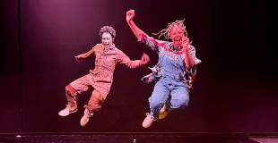 Two dancers perform on stage in colorful clothing