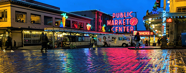 a night shot of pike market with a wet street in the foreground